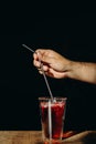 A man hand holding metal straw or stainless straw above a glass of red sweet drink on wooden table Royalty Free Stock Photo