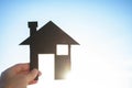 Man hand holding a miniature black model house or home against blue sky and soft sunlight beautiful background for concpept of Royalty Free Stock Photo