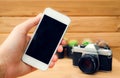 Man hand holding mobile phone blank screen with camera cactus and wood background. Royalty Free Stock Photo