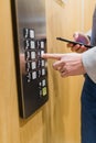 Man hand holding mobile phone while using elevator control panel Royalty Free Stock Photo