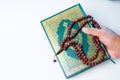 Man hand holding a muslim rosery beads, tasbih with quran asid Royalty Free Stock Photo