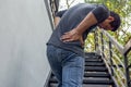 Man hand holding painful back while walking up the stairs.