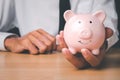 Man hand holding piggy bank on wood table, Concept financial business investment Royalty Free Stock Photo