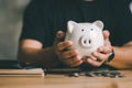 Man hand holding piggy bank on wood table, saving money wealth and financial concept, Business, finance, investment Royalty Free Stock Photo