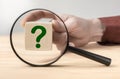 Man hand holding question mark in front of magnifying glass. Search for an answer to question. Research, searching or