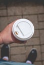 Man hand holding red coffee paper cup, lifestyle summertime shot.