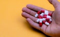 Man hand holding red-white capsule pills on yellow background. Prescription drug. Pharmaceutical business. Drug overdose. Health Royalty Free Stock Photo