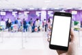 A man hand holding smart phone with background people check in for get on the plane. Smartphone with blank screen and can be add