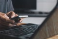 Man hand holding smart phone, and Businessman`s hand using a smartphone for SMS messages with a laptop computer in an office. Royalty Free Stock Photo