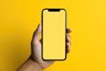 Man hand holding smartphone with blank yellow screen on yellow background. Mockup cell phone screen Royalty Free Stock Photo