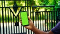 Man hand holding the smartphone with green screen  on the main entrance background Royalty Free Stock Photo