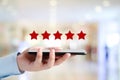 Man hand holding smartphone and red five star over blur background, customer excellent rating satisfacation, customer feedback, Royalty Free Stock Photo