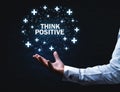 Man hand holding Think Positive words with plus signs.