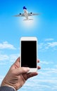 Man Hand holding using mobile phone and airplane on a blue background with white clouds Royalty Free Stock Photo