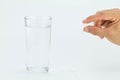 Man hand holding white pill with glass of water on white background Royalty Free Stock Photo