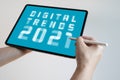 Man hand holding white tablet with Digital Trends 2021 on screen. New trends digital marketing, business and technology concept.