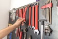Man hand holding wrench. Other tools on the wall