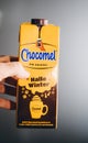 Man hand holding yellow pack of Chocomel chocolate drink against gray background Hallo Winter edition - Dutch dirnk