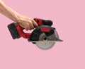 Man hand holds Brushless Cordless circular saw from left top corner on pink color background Royalty Free Stock Photo