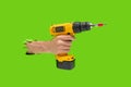 Man hand holds Brushless Cordless Combi Drill that breaks through green color wall