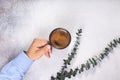 man hand holds a cup of coffee on grey table eucalyptus leaves Royalty Free Stock Photo