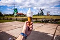 Man hand holds ice cream against background of Dutch wind mills Royalty Free Stock Photo