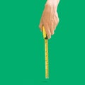 Man hand holds tape measure in inches and centimeters to measure length. Plastic coated steel blade. Hands measuring, Green Royalty Free Stock Photo