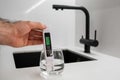 Man hand immerses TDS tester into the water in glass. demonstrates that the water is clean