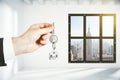 Man hand with key in loft empty room with city view Royalty Free Stock Photo