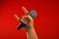 Man hand with microphone and devil horns over red Royalty Free Stock Photo