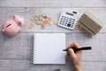 Man hand notepad with coins and piggy bank