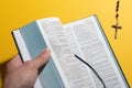 Man hand opening blurred Bible and rosary over yellow Royalty Free Stock Photo