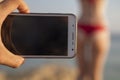 Man hand photographing woman standing back to him in a red