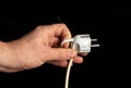 Man hand plug in power plug close up on black background Royalty Free Stock Photo