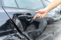 Man hand pointing on car bumper dented broken on black car door