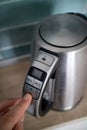Man hand click on the button iron electric kettle on the background of the kitchen Royalty Free Stock Photo