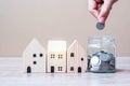 Man hand putting coin in glass jar and wooden house model on table background. Business, Investment, Money Saving, Real Estate and Royalty Free Stock Photo