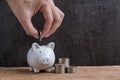 Man hand putting coin into piggy bank with stack of coins towers Royalty Free Stock Photo