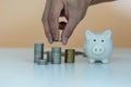 Man hand is putting coins into a piggy bank to save money, saving money for future plans for travel, study, home and retirement. S