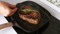 Man Hand Putting Herbs on Grilled Beef Steak with Salt on Grill Pan on Kitchen