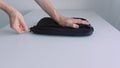 Man hand putting laptop into a case, zipping it up and taking away of the table. Action. Close up of male hand placing