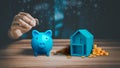 Man hand putting money coin into blue piggy bank for saving money, concept of saving to buy a house. Royalty Free Stock Photo