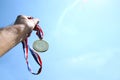 Man hand raised, holding gold medal against skyl. award and victory concept. selective focus. retro style image.