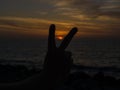 Man hand raising two fingers on sunset background, life is going on concept
