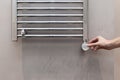 The man hand regulates the temperature in the heated towel rail in bathroom. Royalty Free Stock Photo