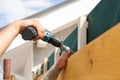 Man hand with screwdriver fastens wooden panel