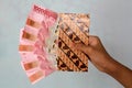 Man hand showing rupiah Indonesian money in a batik envelope. Man hand is holding bunches of Indonesian Rupiah IDR Red 100,000