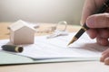 Man hand signing documentation for home mortgage with a pen. Keys and home icon with empty copy space Royalty Free Stock Photo