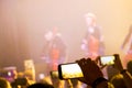 Man hand with a smartphone records a live concert of the group consisting of four cellists and a drummer. The scene is lit with Royalty Free Stock Photo