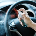 Man hand spraying alcohol sanitizer on steering wheel in his car, against Novel coronavirus or Corona Virus Disease Covid-19. Royalty Free Stock Photo